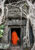 monk going into a rectangular archway in a stoen building and intricate designs are carved in the stone and large tree roots cover the whole side of the temple wall