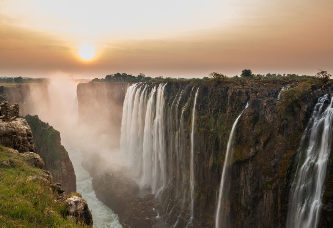 Side view of Victoria Falls with sun setting in distance