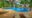 Koh Jum Beach Villas in thailand a large pool with circular edges on a yellow coloured patio and sun loungers with white towels rolled up overlooks a line of trees in the sea is in the distance