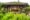 Koh Jum Beach Villas in thailand the front of a hexagon shaped wooden building with open doors on the side looking onto a sofa with lots of cushions and a hedge growing down the bottom
