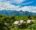 Group of huts in the Vang Vieng countryside are surrounded by greenery and in the background jagged mountains stand against a cloudy sky