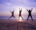 three people jumping in the air on the beach with purple sky behind them