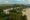 aerial view of a hotel surrounded by green forest but is also on the edge of a beach, featuring villas, pool, golf course