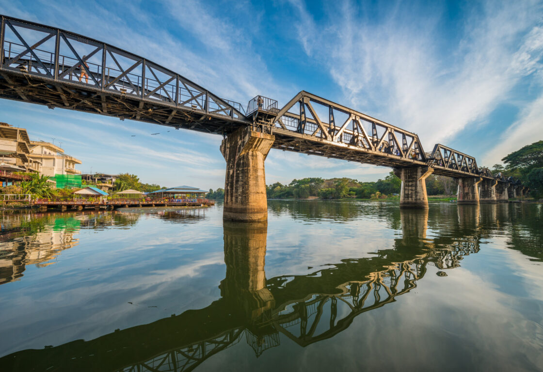 a bridge stretches across a wide river in thailand