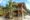a wooden house with pitched roof sits on stilts at Moon Garden Homestay with stairs leading up to it and a tree in front