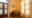 Chambal Safari Lodge in India a small wooden desk with one chair in the corner of a room, large double wooden doors are closed and a floral curtain hides a window on the right hand side