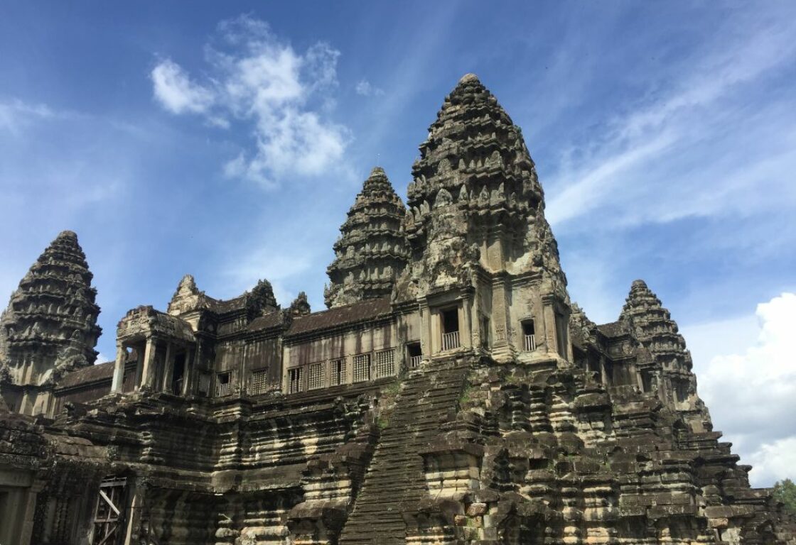 three spires of angkor wat with steep steps and details carved into the stone that leads to a small archway high in the building
