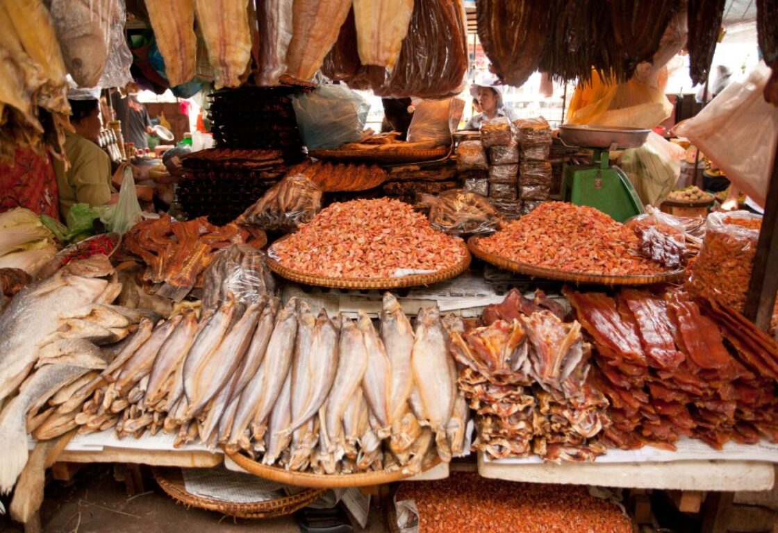array of food and fish spread out on a market table in phnom penh