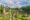 buddha park in vientiane laos has a large open space with grass and trees along the edge is covered with stone statues of buddhist and hindu figures including a large buddha lying down and resting his head on this hand
