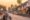 sunset over a busy street in Luang Prabang, Laos with mopeds lined all along the road and white houses with coloured shutters on one side