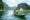 a green boat with tourist in ninh binh travels down a flat river and on either side of the water tall formations rise covered in trees