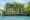 Viroth's Hotel in cambodia a white building with a pool and loungers stretching out in front and with tall palm trees growing in front