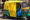 a bright tuk tuk in the streets of delhi with a yellow roof and bottom of the vehicle is green