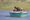 Chambal Safari Lodge in india a blue boat on a lake with four peole inside, one with binoculars looking for wildlife