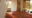Flame of the Forest in india the end of a double bed with mosquito net hanging down and an armchair facing an open door leading to trees