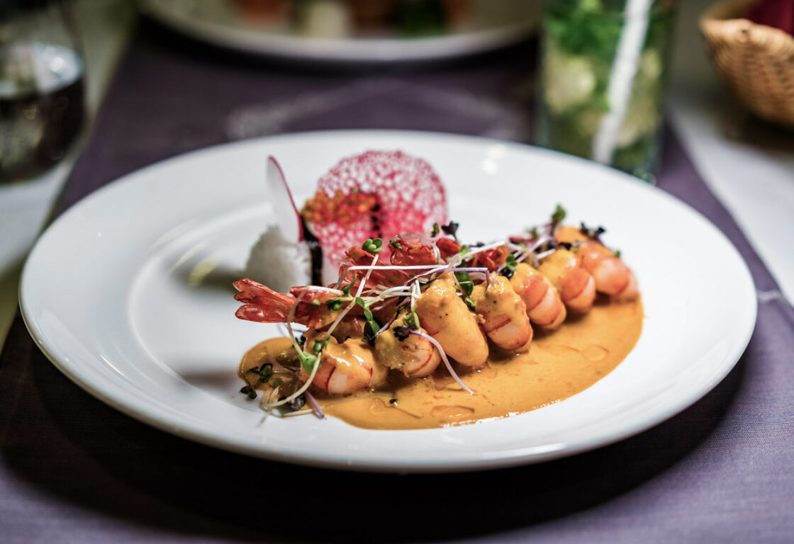 a plate of food with prawns lined up and a sauce drizzled over