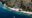 Komodo Resort in indonesia a stretch of sand and a hilly landscape behind and along the line of the hill on the beach are huts of different sizes all looking onto the sea and in the middle a pier goes into the water