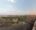 Panoramic view from Ramathra Fort across the Rajasthan countryside, featuring ancient stone walls, farmland, rolling hills and a lakeside landscape.