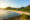 a long beach on lombok in bali with greenery and a hill growing behind the white sand
