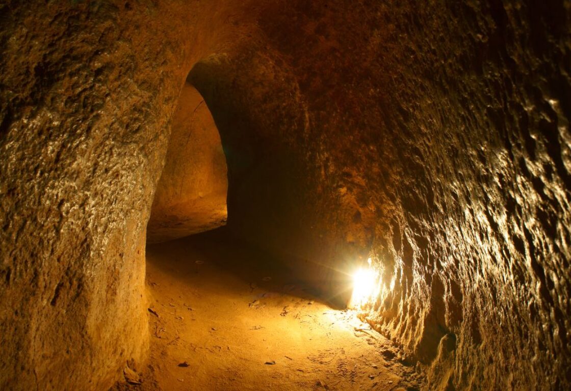 underground caves in ho chi minh with sand walls and a small passage and one light is on to show the way