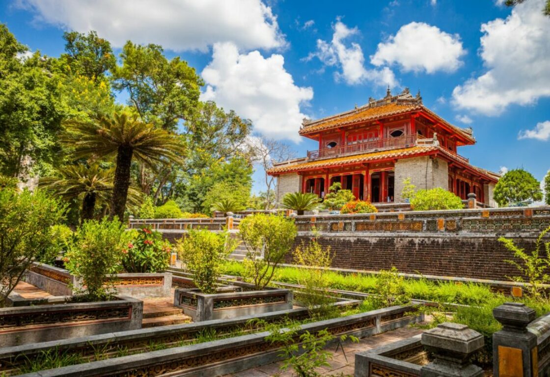 view of a tomb in the distance with small gardens and a tree in front