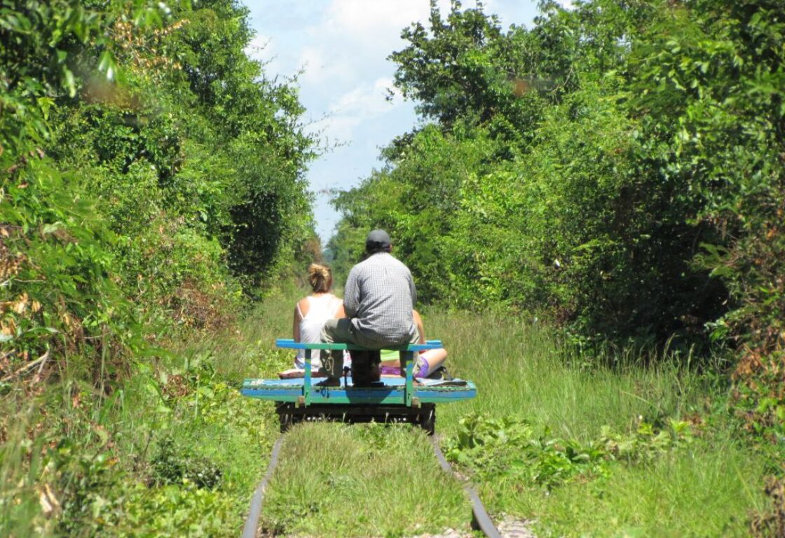 people on a flat piece of wood going down an abandoned railway