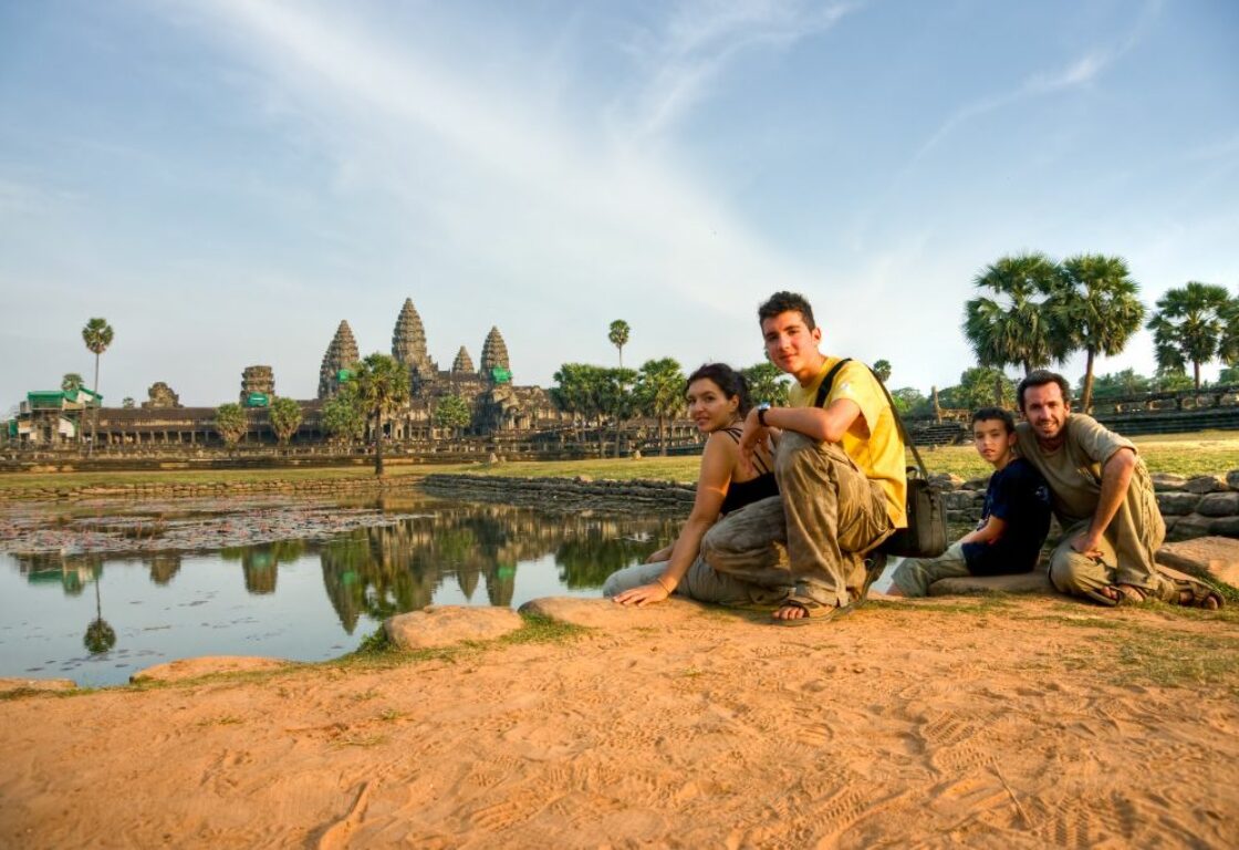 father of two sons and daughter sat together with angkor wat in the distance, cambodia