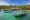 wooden boats moored at sea with a pier in the background onto a palm tree fringed beach