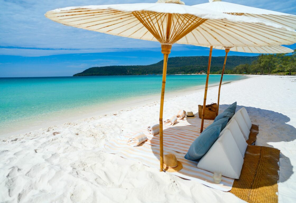 pristine white sand with towels and cushions under umbrellas and with clear sea rolling out in front