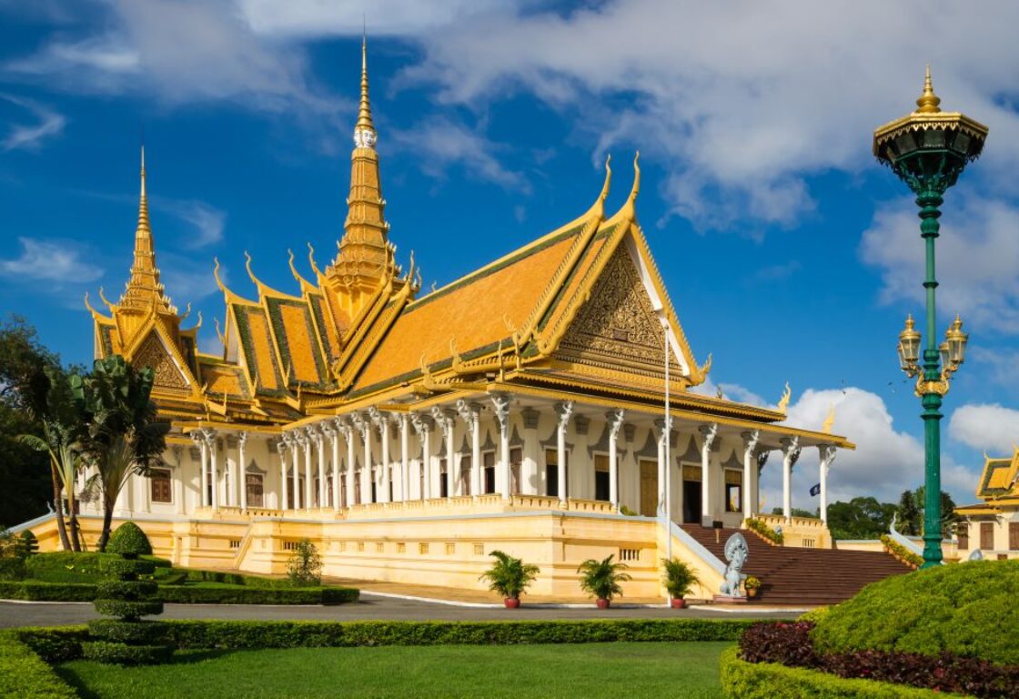 golden royal palace in phonm penh cambodia with a gold roof and columns all round the outside, set in gardens