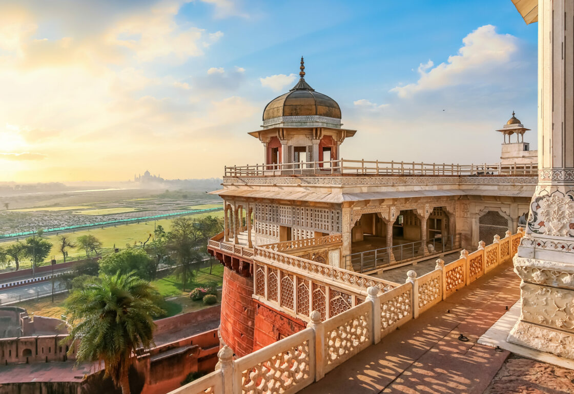fortress with high walls and arched gateways of agra fort and the taj mahal far in the distance