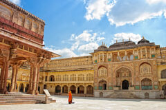woman stands in the amber fort in Jaipur, Rajasthan, in front of a detailed gateway designed with mosiacs and detail in india