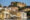 buildings up a river bank in udaipur, india, with a palace at the top of the hill