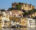 buildings up a river bank in udaipur, india, with a palace at the top of the hill