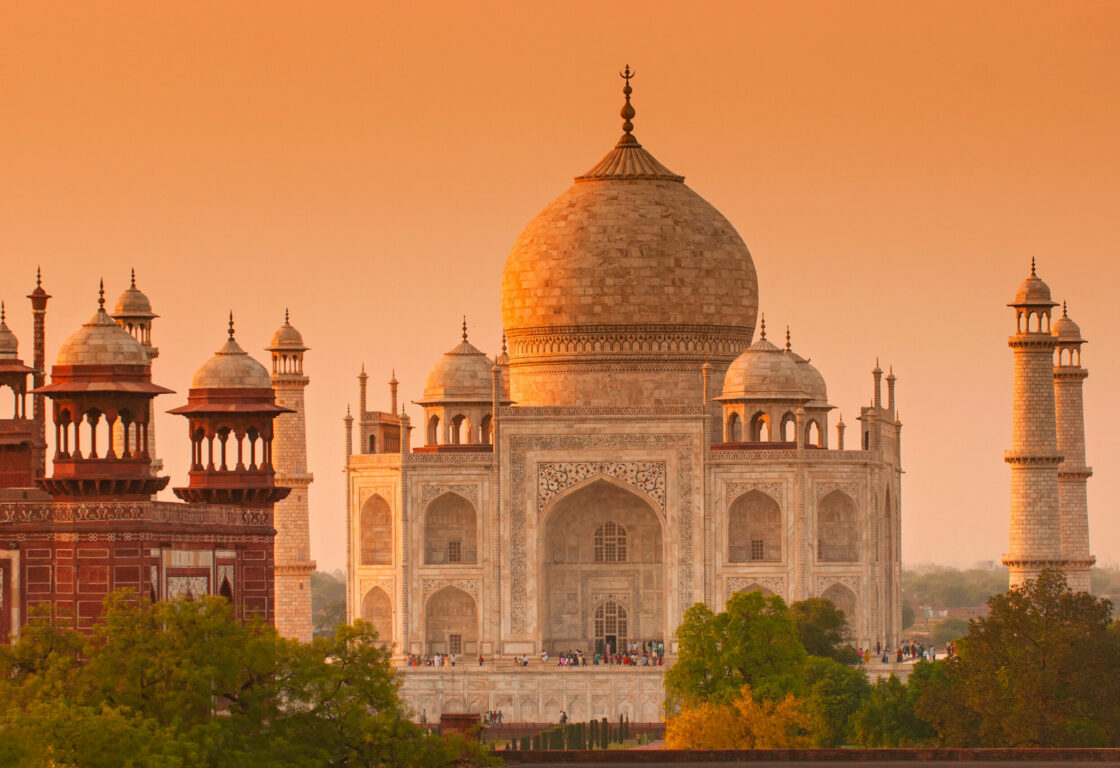orange sunrise over The Taj Mahal in india, a white marble mausoleum with a large central dome and four minarets