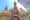 in the front of the image are what looks like upside down shuttlecocks and in the background a tall triangle goes in to the sky with bright colours and traditional balinese symbols including two small faces of dragons