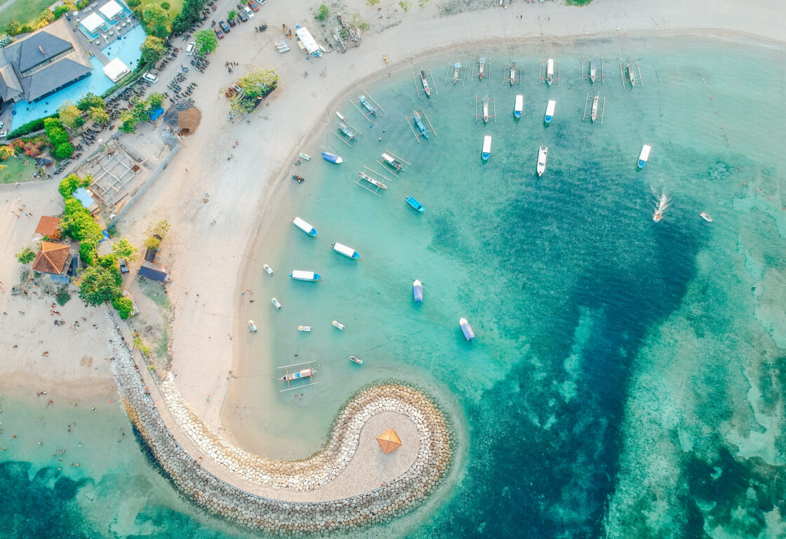 aerial view of Sanur beach with little boats dotted around the sea and a path leading out and circling in the sea