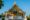 a large temple in laos with a pointed roof and the front is decorated in ornate gold and green decorations and steps lead up to archways in the front