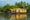 an indian houseboat with a bamboo shell along a river with palm trees in the background
