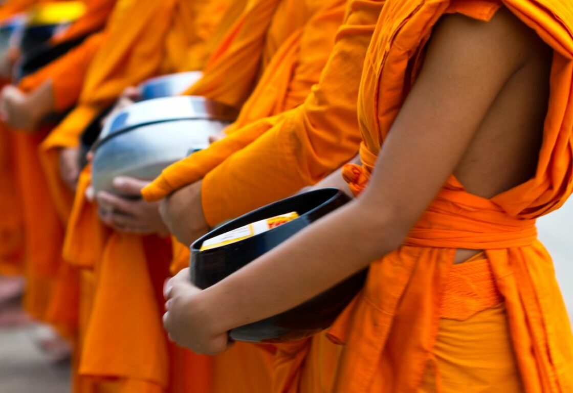 monks holding bowls waiting in a queue in luang prabang