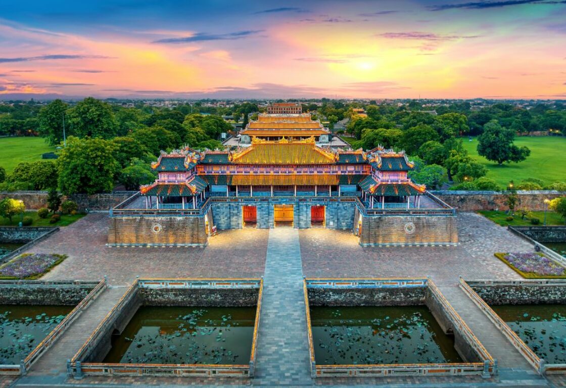 aerial view of a big temple with a large pond in the front and trees in the background