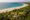 aerial view of the ocean, beach, palm trees and The Last House tucked away inbetween with a swimming pool