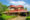 Mundakal Homestay property view featuring a brick buidling with red tiled roof and lush green gardens