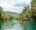 Loboc River in Bohol, Philippines a wide river lined with forests on both banks and a hill at the end and on the river there is a bamboo hut and next to that another bamboo hut over the water