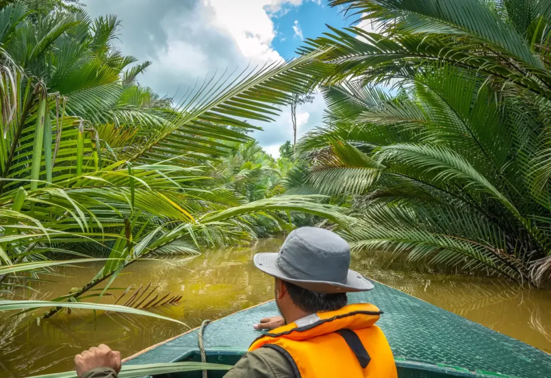 a man in an orange vest cruising on the river in Borneo