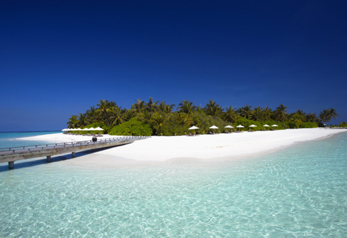 white sandy beach and crystal clear waters surrounding a small island in the Maldives