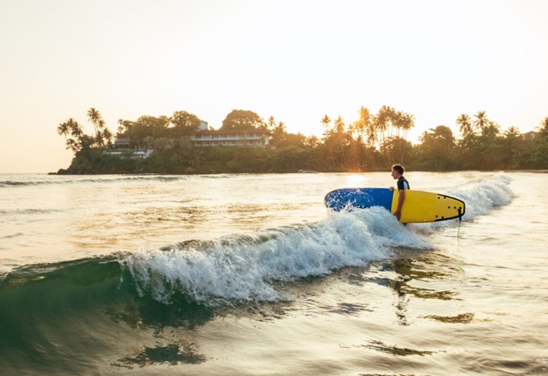 surfer standing in the ocean holding a surf board
