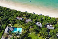 aerial view of a beach resort located in greenery but right on the beach a walking distance to the ocean