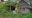 an outside view of a private lodge for two in the trees made out of wooden roof, stone walls and surrounded by trees