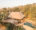 aerial view of a luxury safari lodge made out of wood and tached roof set in the middle of an african bush with a swimming pool in front of it
